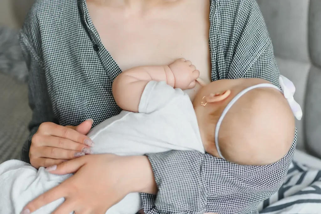 Breastfeeding mother holding baby showing benefits of breast milk for health and development